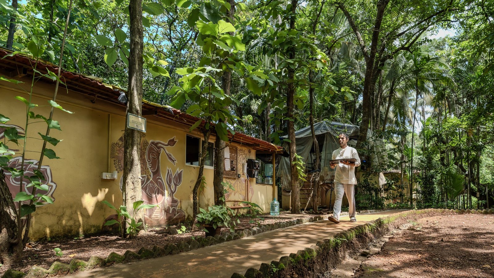 Retreat host walking between cottages beneath the trees